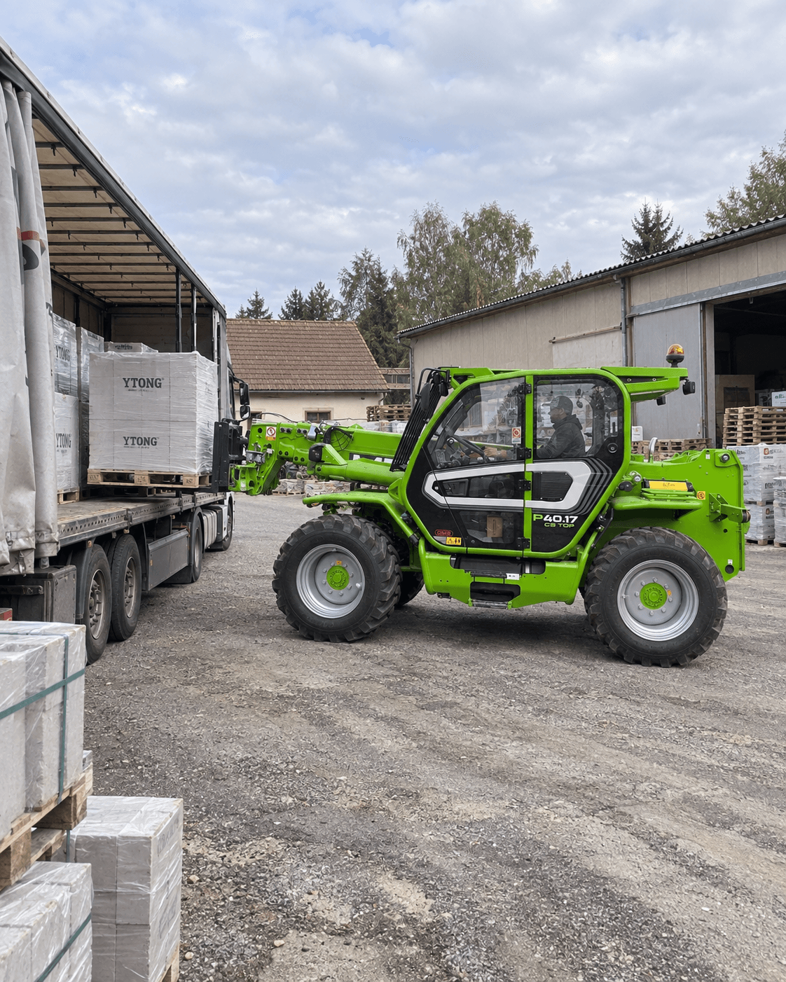 Merlo P40.17 vykládá paletu materiálu z návěsu kamionu na staveništi